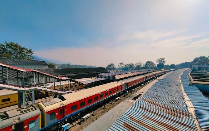 Kathgodam Junction platforms with a train at the platform and the Kumaon foothills behind, the arrival point for the overnight Ranikhet Express