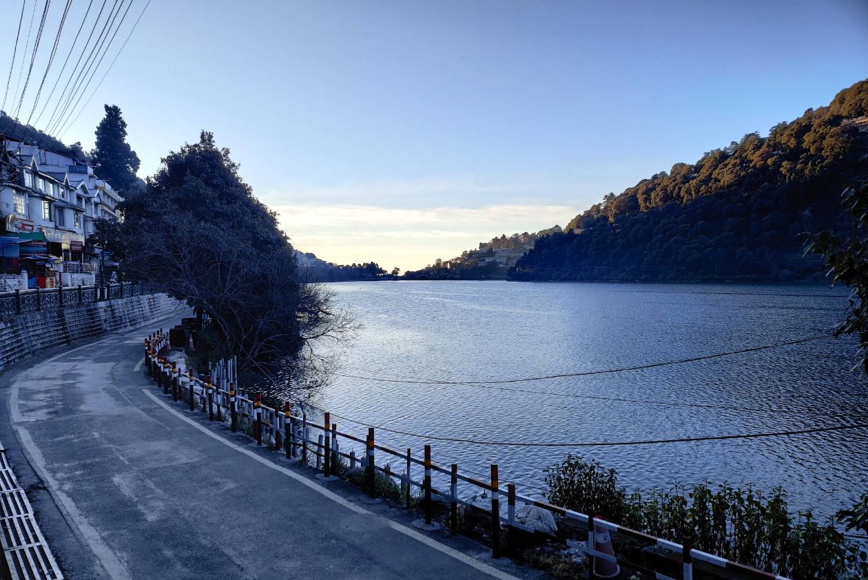 The lakeside Mall Road at the Mallital end of Nainital, hotel frontages on the left and Naini Lake filling the frame, the belt where couple-friendly rooms sit